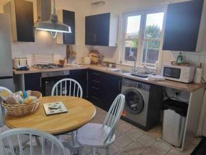 a kitchen with a table and a stove and a microwave at 2 Bedroom Cosy Cottage in Rearsby