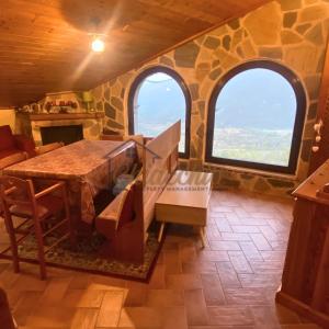 a dining room with two windows and a table at La Baita sulla Neve - Posto Auto in Rocca Cinquemiglia