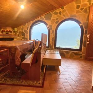 a room with two windows and a table and a bench at La Baita sulla Neve - Posto Auto in Rocca Cinquemiglia