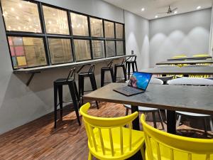 Coliwo Trois - Kharadi في بيون: غرفة طعام مع كراسي صفراء وجهاز كمبيوتر محمول على طاولة