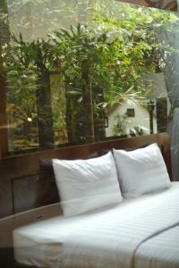 a bed with white pillows in front of a window at Hapu Garden homestay in Buôn Enao