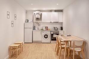 a kitchen with white appliances and a table and chairs at Ajuda Charm Apartment with Garden in Lisbon
