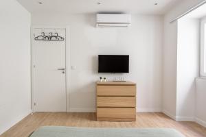 a living room with a tv and a wooden dresser at Ajuda Charm Apartment with Garden in Lisbon