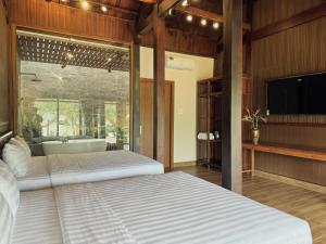 a bedroom with two beds and a tub and a television at Hapu Garden homestay in Buôn Enao