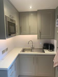 eine Küche mit weißen Schränken und einem Waschbecken in der Unterkunft The Coach House in Warnham