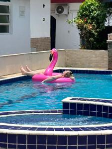 Uma mulher a flutuar num flamingo cor-de-rosa numa piscina. em Villa Di Verona Charm Hotel no Guarujá