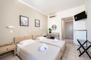 twee bedden in een hotelkamer met een televisie bij Zephyros Hotel in Kos-stad