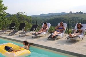 eine Gruppe von Frauen, die an einem Pool auf Stühlen sitzen in der Unterkunft Villa La Gioiosa in Montelupo Albese