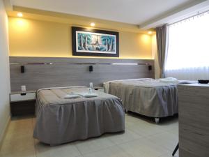 una camera d'albergo con due letti e una TV a parete di RESIDENCIAL CARMANI a Tacna