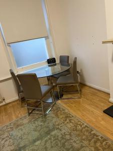a glass table and chairs in a room with a window at Property minutes from Hammersmith and Kensington 2 in London