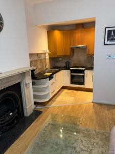 a kitchen with wooden cabinets and a fireplace at Property minutes from Hammersmith and Kensington 2 in London