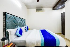 1 dormitorio con 1 cama grande con almohadas azules y blancas en Hotel Mini Residency - Hari Nagar Ghanta Ghar en Nueva Delhi