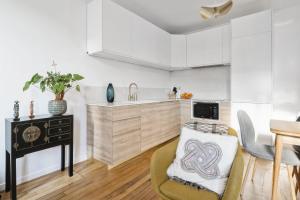 a kitchen with white cabinets and a table at Appartement Lutèce - Welkeys in Vincennes