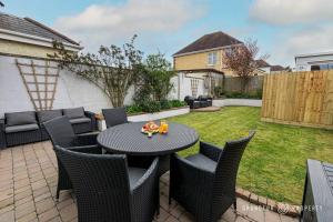 eine Terrasse mit einem Tisch und Stühlen im Hof in der Unterkunft 3 Bed House, Large Garden, Parking, Wi-Fi, Poole - Sarnia Retreat in Poole