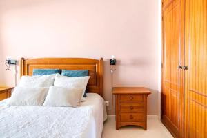a bedroom with a bed with a wooden headboard and a table at Fantástico T2 AC Wi-FI e TV Cabo 2WC Toalhas e Lençóis in Altura +10 photos