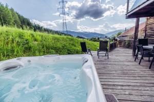 einen Whirlpool auf einer Holzterrasse mit einem Tisch und Stühlen in der Unterkunft Woody Park in Sankt Georgen ob Murau