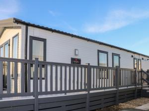a white house with a wooden fence at Chichester Lakeside Holiday Park in Chichester