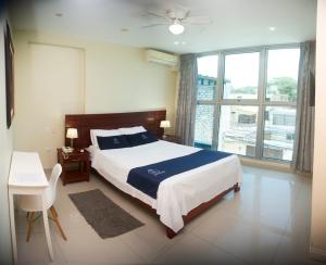 a bedroom with a bed and a table and a window at LC Hoteles Piura in Piura
