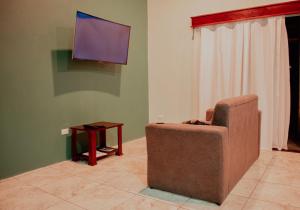 a living room with a chair and a flat screen tv at Wild Arenal Village in Fortuna