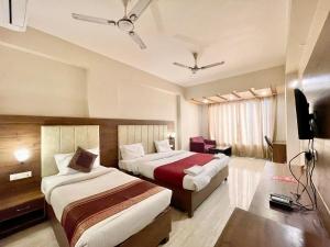 a hotel room with two beds and a television at Hotel Rudraksh ! Varanasi ! fully-Air-Conditioned hotel at prime location with Parking availability, near Kashi Vishwanath Temple, and Ganga ghat in Varanasi