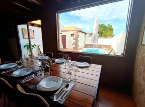 a table with plates and wine glasses and a window at Villa Enola in La Oliva