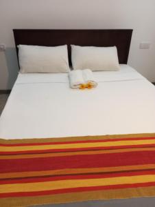 a bed with two towels and a flower on it at Nade Villas Ahungalla in Ahungalla