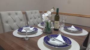 un tavolo con piatti e bicchieri e una bottiglia di vino di Lalovina Apartment a Herceg-Novi