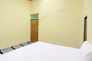 a white bed in a room with a door at OYO J.M.D Restaurant &rooms in Jhājhar