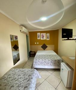 a hotel room with two beds and a flat screen tv at Hotel Jovilá in Jaraguá do Sul