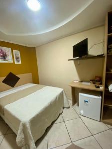 a bedroom with a bed and a tv on the wall at Hotel Jovilá in Jaraguá do Sul