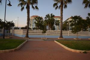 una valla con palmeras frente a un edificio en Luxurious Spacious Three Bedroom Apartment On Beachfront, en Almerimar