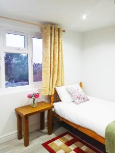 Goodmayes的住宿－Goodmayes Park Home，一间卧室配有一张床、一张桌子和一个窗户。