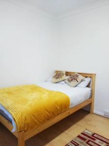 Un dormitorio con una cama con una manta amarilla. en Goodmayes Park Home en Goodmayes
