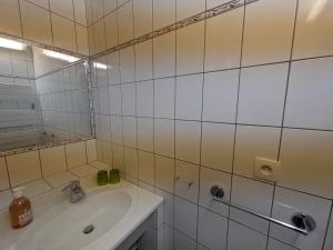 波旁莱班Appartement 3 étoiles tout confort, près des thermes, avec toit-terrasse ensoleillé à Bourbonne-les-Bains - FR-1-611-97的配有水槽和镜子的白色瓷砖浴室 更多6张照片