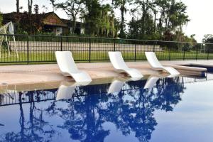 two white chairs sitting next to a swimming pool at Finca Hotel Los Girasoles in Montenegro
