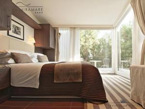 チェルヴィアにあるHotel Miramare - SPA & Suites - Breakfast & Brunch Until 13-00のベッドルーム(大型ベッド1台、大きな窓付)