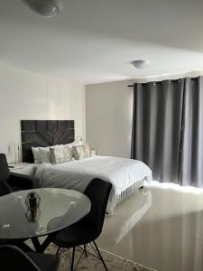 a white bedroom with a bed and a table at 135 on Millennial Umhlanga in Durban