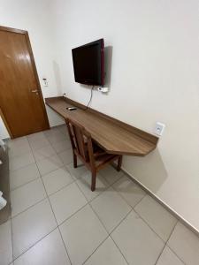 een kamer met een houten bureau en een tv aan de muur bij Hotel Guanabara Palace in Andradina