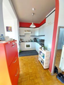 a kitchen with white cabinets and red accents at Wonderful stay Monet in Ghent