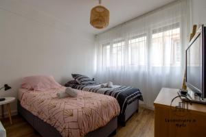 two beds in a small room with a tv and window at Au cœur des Lices in Albi