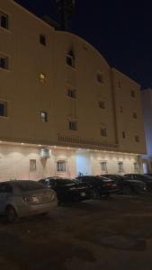 a large building with cars parked in a parking lot at Narcissus suite in Riyadh