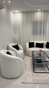 a living room with two white chairs and a coffee table at Narcissus suite in Riyadh
