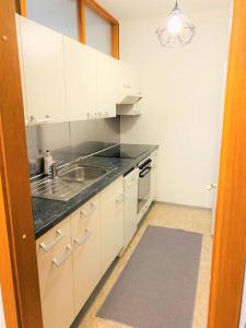 eine Küche mit weißen Schränken und einem Waschbecken in der Unterkunft Charmante Wohnung in St. Peter. in Graz
