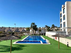 a swimming pool with two umbrellas next to a building at Casa Onesta Luxery apartment with private rooftop terrace in Orihuela