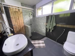 ein Bad mit einem Waschbecken, einer Dusche und einem WC in der Unterkunft Kowlessur Residence in Surinam