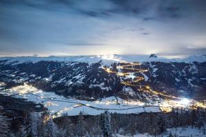 a view of a snowy mountain with a city at night at Appartement Stefanie in Hollersbach im Pinzgau