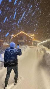 una persona che scatta una foto nella neve con un cellulare di Ahşap villa a Tepecik