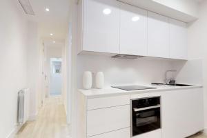 a white kitchen with white cabinets and a stove at FUENCARRAL II in Madrid
