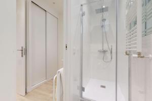 ein weißes Bad mit einer Dusche und einer Glastür in der Unterkunft FUENCARRAL II in Madrid