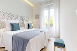 a white bedroom with two beds and a window at FUENCARRAL II in Madrid